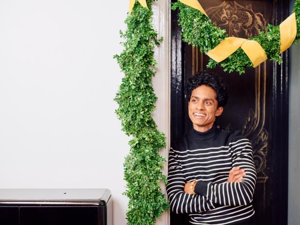 Man Stands Beneath Real Garland in Doorway Posing to Camera