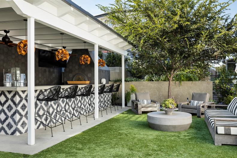An Outdoor Kitchen in a Lush Backyard Features Modern Accents 