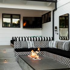A Back Patio Features a Built-In Bench That Surrounds a Modern Poolside Fire Pit