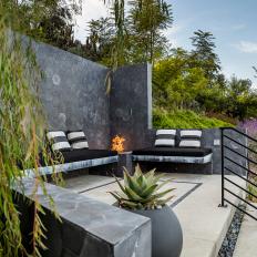  An Open-Air Patio Features Tiled Privacy Walls, Built-In Benches and a Fire Pit Built Into the Corner of the Space