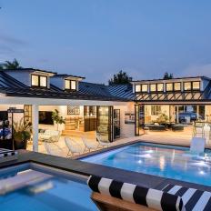 A Modern Backyard, That’s Connected to the Indoor Living Area With Walls of Sliding Doors, Features a Swimming Pool and Multiple Sitting Areas