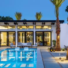 A Contemporary Backyard Features a Large Swimming Pool, a Lounge Area and Palm Trees