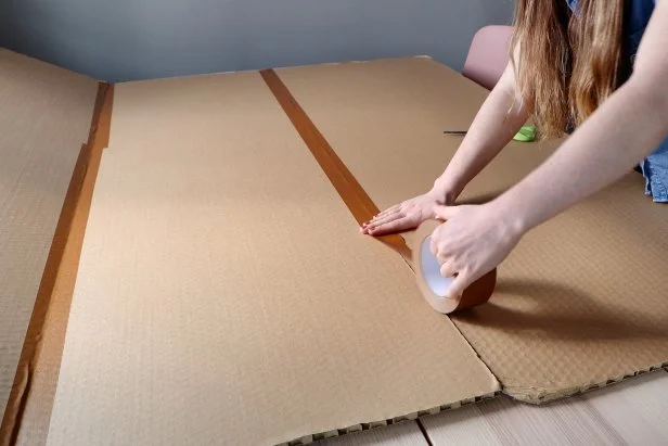 Line up the three panels and tape them together on one side to make a tri-fold board. You can use duct tape, packing tape, or any other sturdy tape that you have.