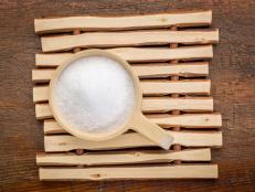 Epsom salts (Magnesium sulfate) in a rustic wooden scoop - relaxing bath concept