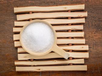 Epsom salts (Magnesium sulfate) in a rustic wooden scoop - relaxing bath concept