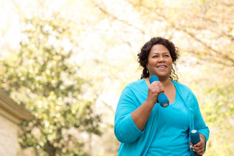 Woman Walking Outdoors With Hand Weights