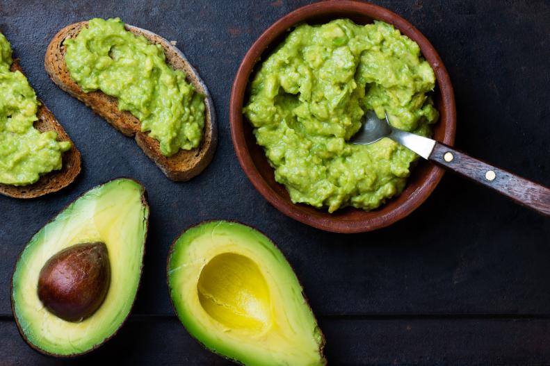 Smashed avocado in a bowl and on toast