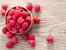 A wooden bowl of fresh red raspberries
