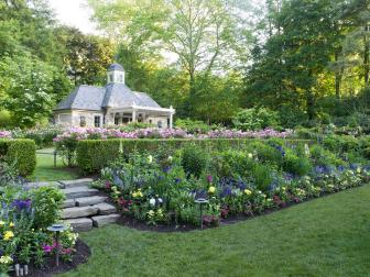 A Backyard Garden Features Tiered Flower Beds and a Stone Garden House