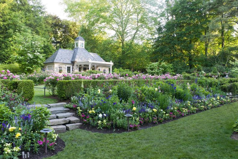 A Backyard Garden Features Tiered Flower Beds and a Stone Garden House