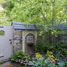 A Cottage-Style Garden Features Flagstone Walls, a Wood Garden Gate and Vibrant Flower Beds