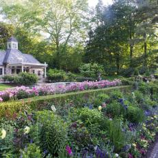 A Cottage-Style Garden Features Vibrant Flowers and a Large Stone Garden House