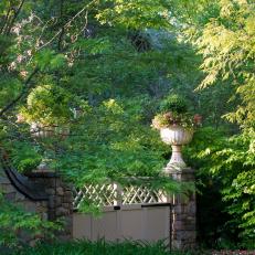 A Backyard Garden Is Surrounded By a Flagstone Wall and Features Wood Garden Gates