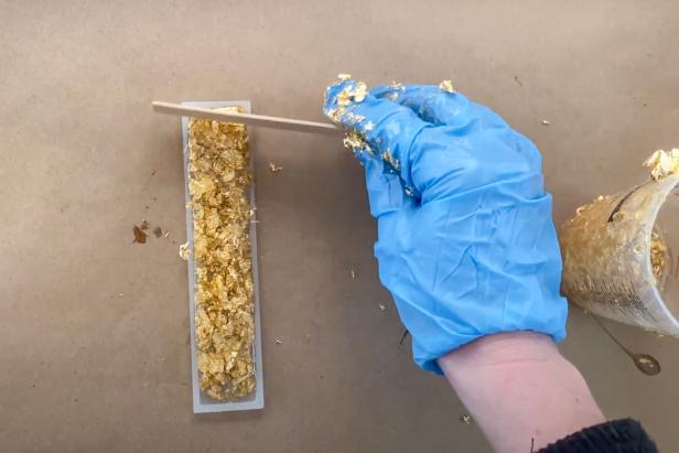 Create a glam gold flake bookmark by mixing a cup of gold flakes into remaining resin. Pour into the skinny bookmark mold and let dry overnight.