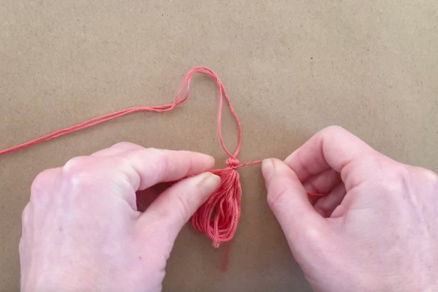 Trim another small piece of floss and tie it tightly around the top of the bundle to create the tassel look. Cut the embroidery floss bundle in the middle and even up the ends with scissors.