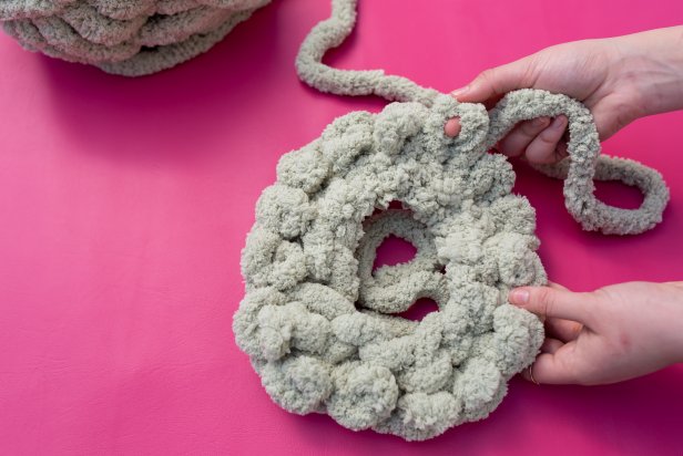 Next, put the yarn in a circle. Take the working yarn and put it through the first loop to connect the two sides of the chain. Now, push the yarn through the outer loops that were just made to make another loop. Continue around the full circle until 15 rows are completed. Tip: Make small loops to better hide the filling inside.