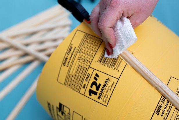 Wipe any excess wood glue after clamping with a tissue. Continue to glue and clamp the wooden trim around the tube until it is covered. Let dry completely.