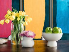 Bright colors in the room’s modern painting are echoed in the flowers and fruit found on the dining table.
