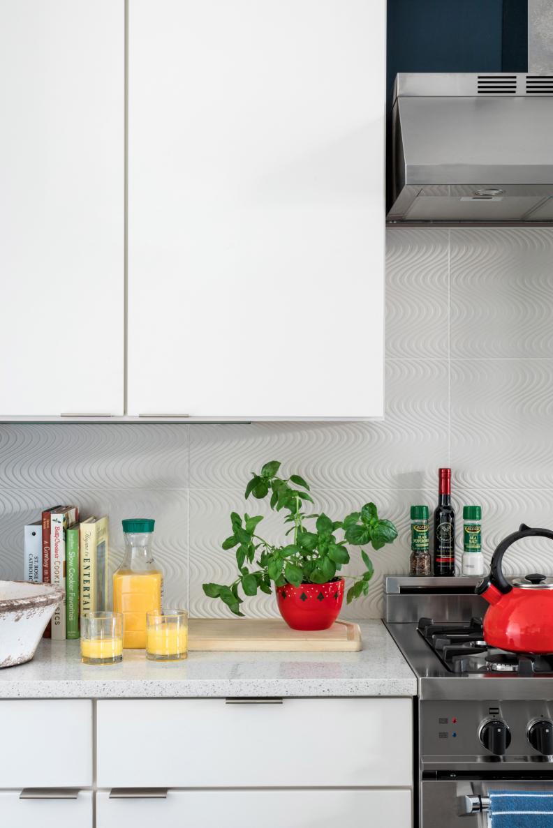 Whether you're a property owner renting to short-term tenants or a renter looking to make some temporary changes, keep in mind that classic color combinations have the most staying power. This kitchen's back wall was painted navy blue; countertop accessories in red were added for a timeless, Americana palette. 
