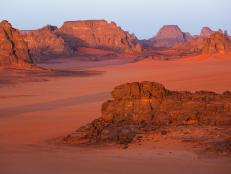 Rock formations glow over the Algerian Desert at dusk