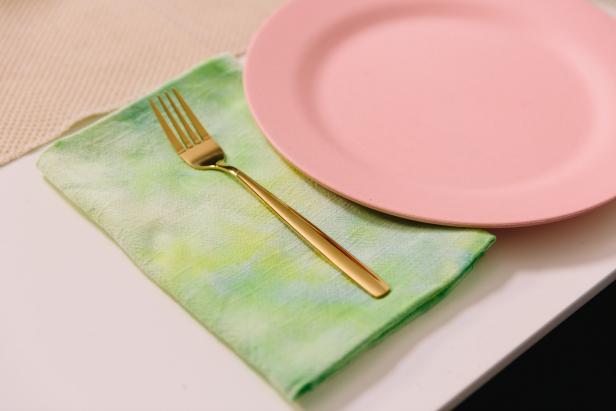 Pastel Table Setting With Tie-Dye Napkins Folded Beside Pink Plates