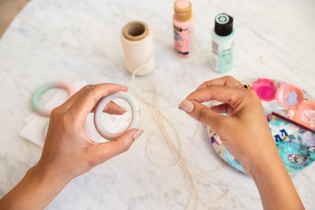 Next, trim off three pieces of 3’’ of baker’s twine. Fold the baker’s twine in half and create a loop knot over the top ring. Make a total of three knots.