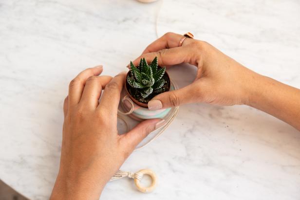 Finish the hanging planter with a small 1’’ ring tied to the strings at the top. Then add your favorite succulents in a small terra cotta pot.