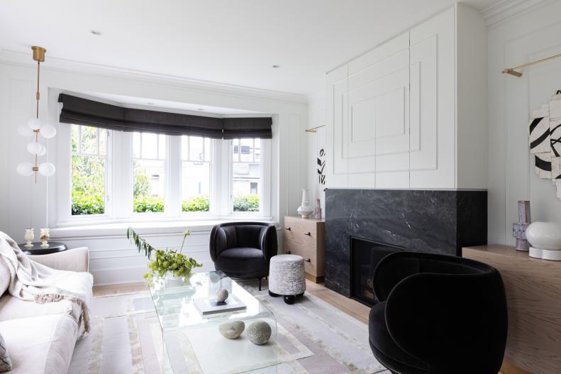 White living room with black velvet accent chairs marble fireplace