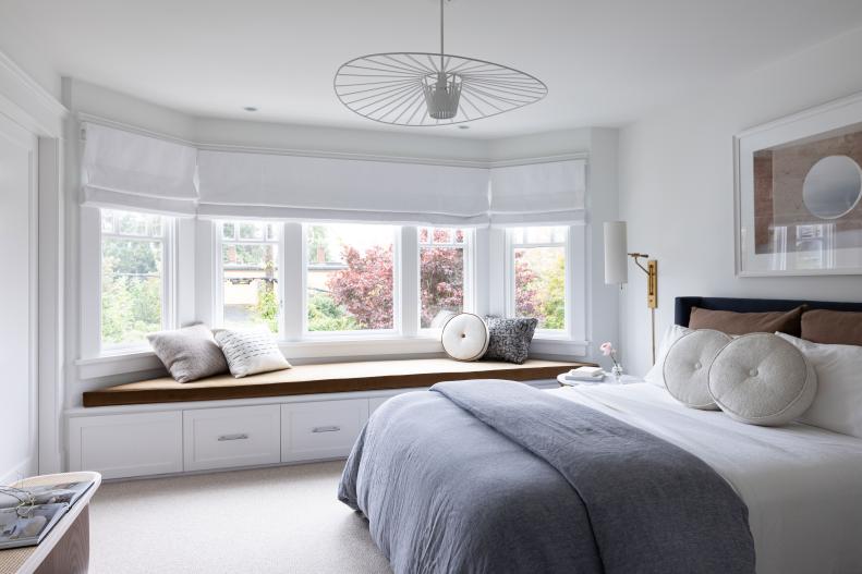 Guest bedroom with large window seat and circular light fixture