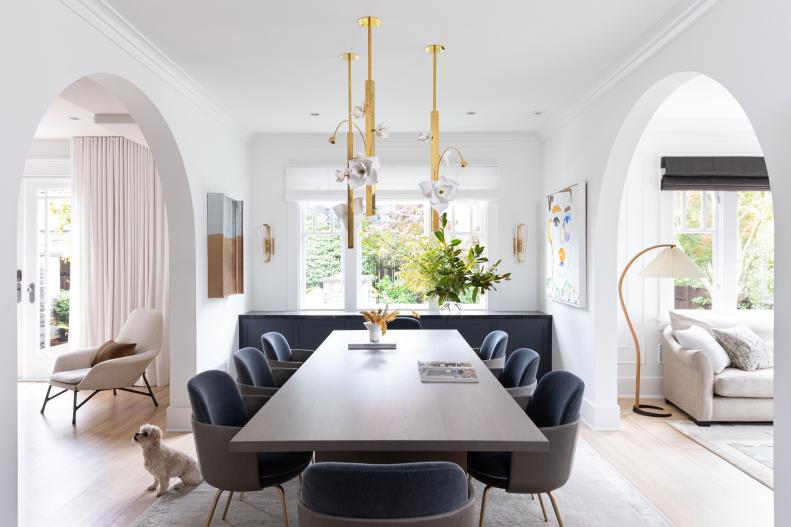 A white dining room with a large gold light fixture with white flowers.