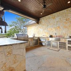 Rustic Stone Outdoor Kitchen With TV