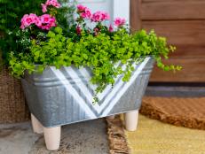 Give your front porch decor a budget-friendly facelift by upcycling a plain metal bucket into a fresh, modern planter. All you need is paint, a stencil and some inexpensive furniture feet.
