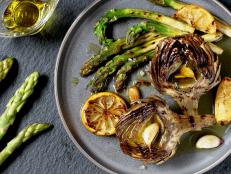 Grilled artichokes and asparagus on a plate with lemons