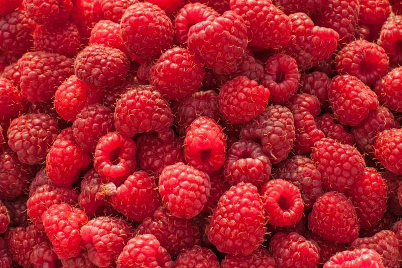 A pile of raw red raspberries