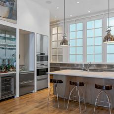 Kitchen Features a Large Marble-Topped Island and Stainless Steel Cabinets 