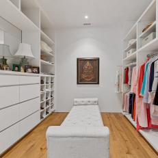 Walk-in Closet Features White Built-Ins and an Upholstered Bench 