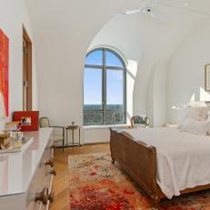 White Bedroom Features Arched Window and Colorful Artwork