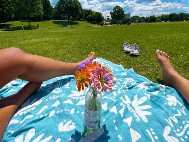 Feet stretch across a beach towel styled with a flower arrangement