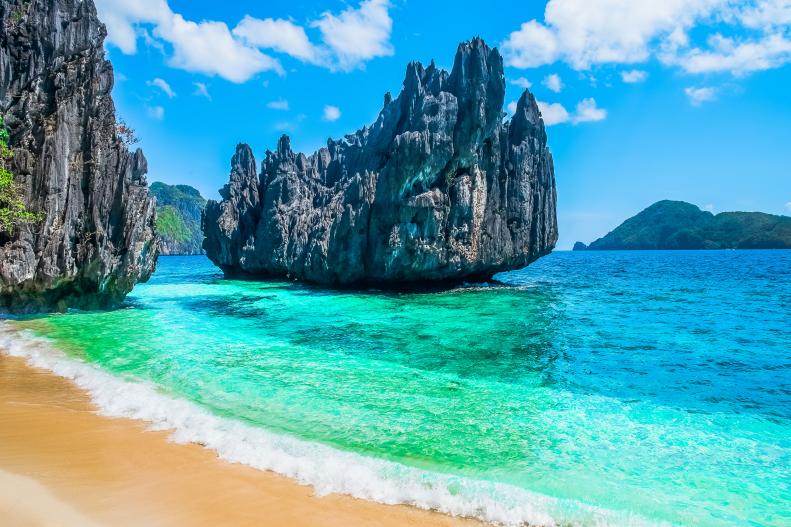 Rocky outcrops amidst turquoise seas and a lazy beach in Palawan