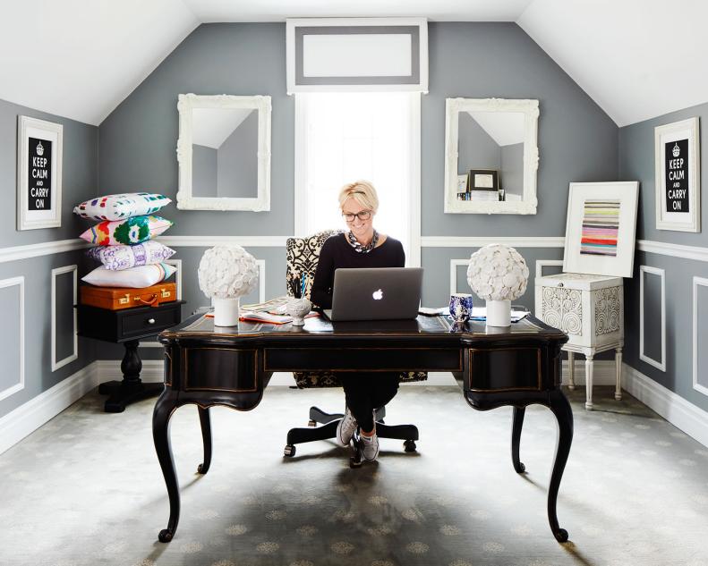 Blonde woman sitting at dark wooden desk in grey office.
