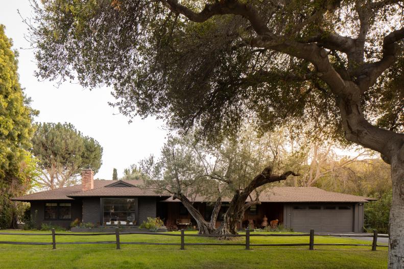 A California ranch-style house with green, manicured lawn, large tree