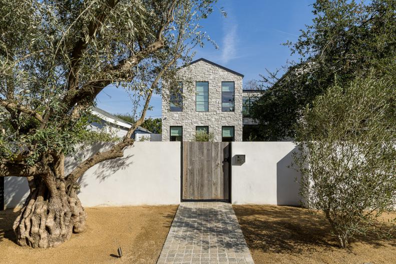 This LA home features a stone exterior and custom plaster fence.