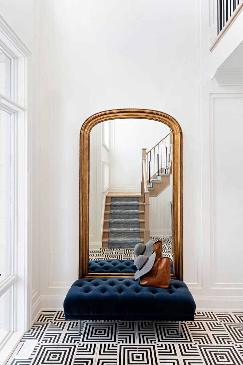 This foyer features an oversize gold mirror and a black-and-white floor.