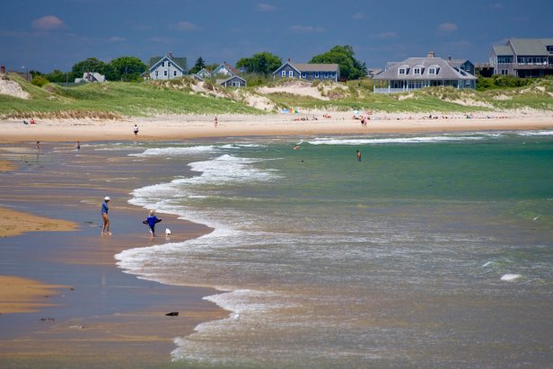 People playing in gentle surf in front of beach houses on Block Island