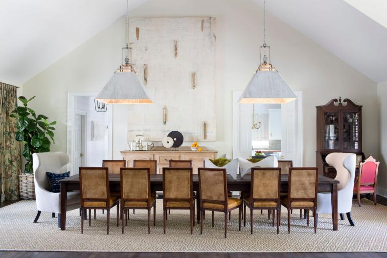Long wooden table with white pendants and 14 chairs.