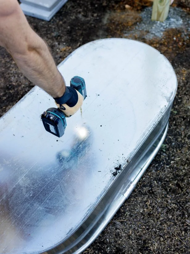 Drilling drainage holes into the bottom of the galvanized tub. 