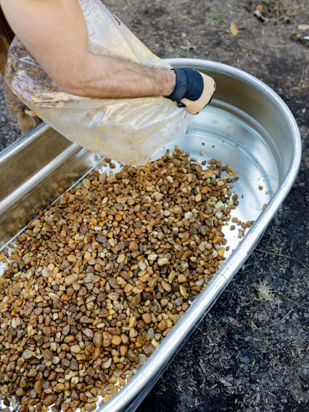 Adding rocks to the bottom layer of the raised plant bed. 