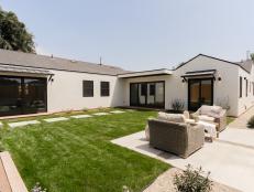 A white stucco home with grassy courtyard, concrete slab seating area