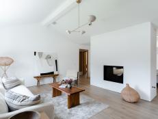 A white, minimalist living room with vaulted ceilings and fireplace