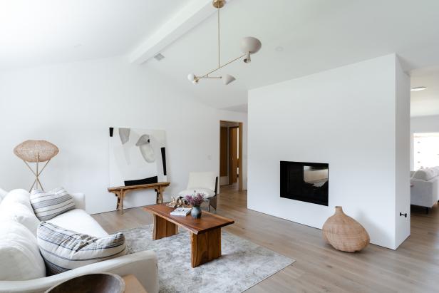 A white, minimalist living room with vaulted ceilings and fireplace